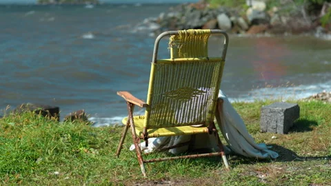 Deck chair mockup on a grass beach with blue sea background, rear view Stock-Footage 345624897
