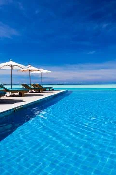 Deck chairs and infinity pool over amazing lagoon Stock Photos