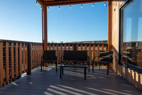 A deck with chairs and a table with a view of the mountains in the background Stock Photos