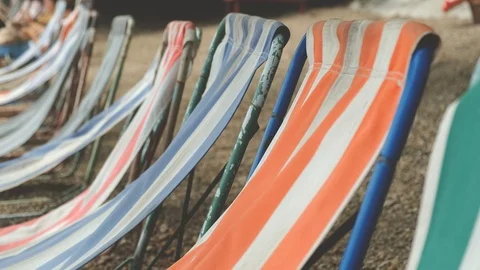 Deck chairs are blown by the wind on a pebble beach Stock Footage 113665498