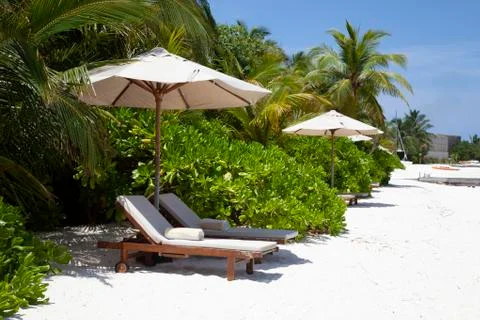 Deck chairs under umbrellas on the beach at maldives Stock-Fotos