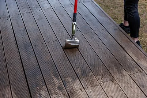 Deck cleaning in progress with long handled metal head brush Photos