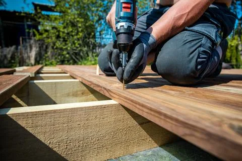 Deck construction, builder hand with electric screwdriver installing impreg.. Stock Photos