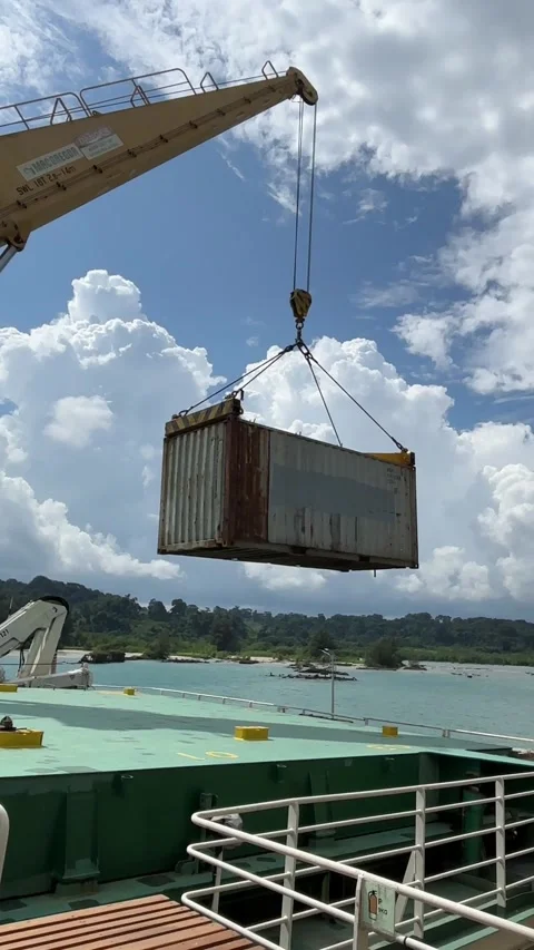 Deck Crane Lifting Cargo Container Onto Ship at Port on a Bright Sunny Day Stock Footage 324840719