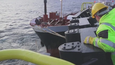 Deck crew takes mooring cable from tanker for bunkering Stock Footage 121117236