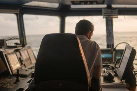 Deck navigation officer on the navigation bridge. He looks at radar screen Stock Photos