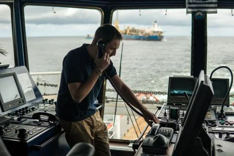 Deck navigation officer on the navigation bridge. He looks through binoculars Stock Photos