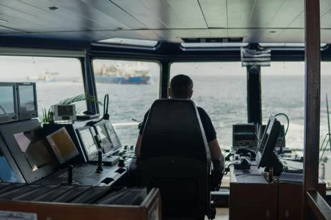 Deck navigation officer on the navigation bridge. He looks to sea Stock Photos
