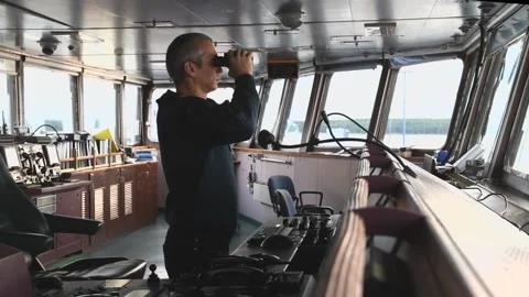 Deck officer with binoculars on navigational bridge. Seaman on board of vessel. Stock Footage 220492210