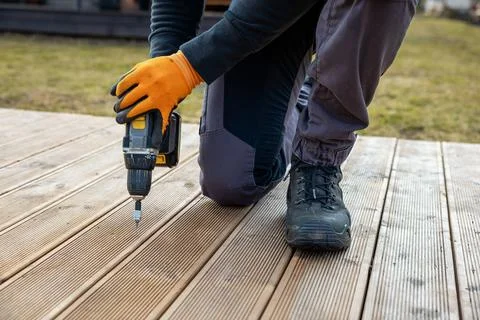 Deck or terrace construction, builder hand with electric screwdriver instal.. Stock Photos
