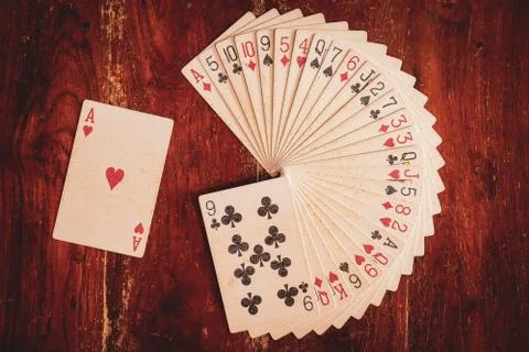 Deck of playing cards arranged in circular stack on wooden table for illusion. Фото