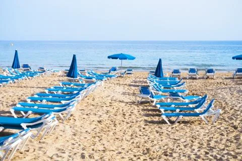 Deckchairs on the beach sand at sunset Stock Photos