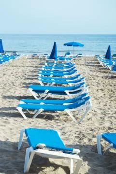 Deckchairs on the beach sand at sunset Stock Photos