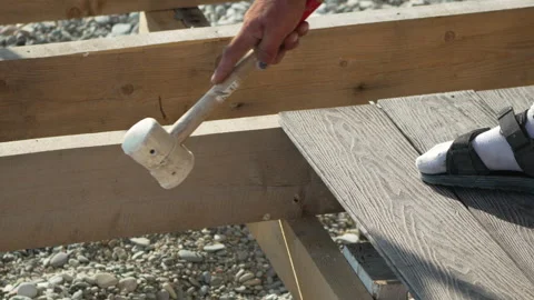 Decking Mallet Installation Hand hammering composite board on wood joists Stock Footage 314937495