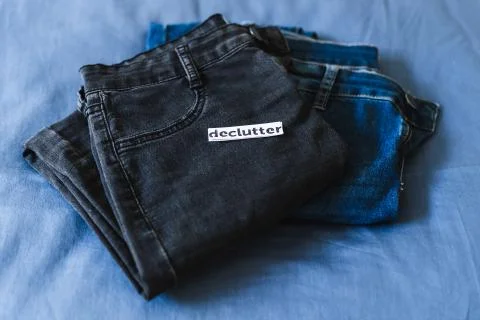 Declutter label on different jeans in various denim colors, tidying up concep Stock Photos