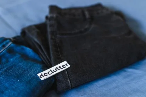 Declutter label on different jeans in various denim colors, tidying up concep Stock Photos