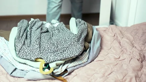 Decluttering process: Woman taking clothes on hangers out of wardrobe and puttin Stock Footage 332440667