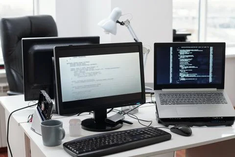 Decoded data on computer and laptop screens standing on workplace of programmer 写真素材