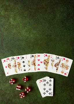 Decomposed deck of playing cards and red dice on green textured Stock Photos