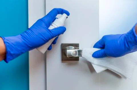 Decontaminating the surface of the door handle. Stock Photos