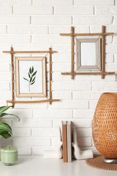 Decor elements and books on white table near brick wall with stylish bamboo f Foto stock
