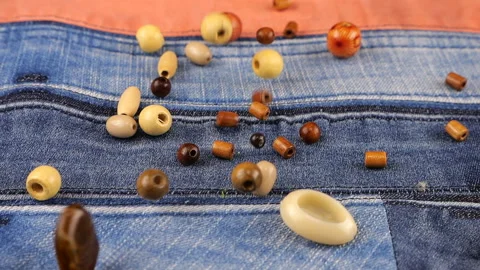 Decor elements made of natural materials, wood and shell beads fall on denim.  Video stock 229486560