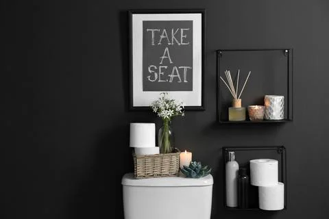 Decor elements, necessities and toilet bowl near black wall. Bathroom interio Stock Photos