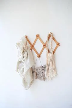 Decor items hang on a white wall on a wooden hanger. Macrame , towels. Rustic Stock Photos