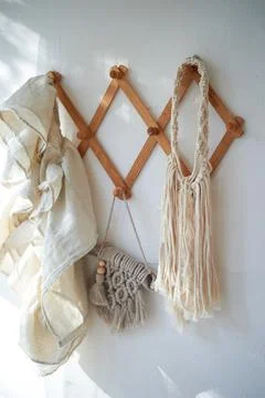 Decor items hang on a white wall on a wooden hanger. Macrame , towels. Rustic Photos