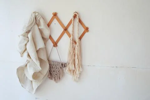 Decor items hang on a white wall on a wooden hanger. Macrame , towels. Rustic Stock Photos