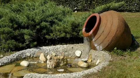 The decor in the Park. Slow motion from a large jug of water flows and becomes a Stock Footage 92155731