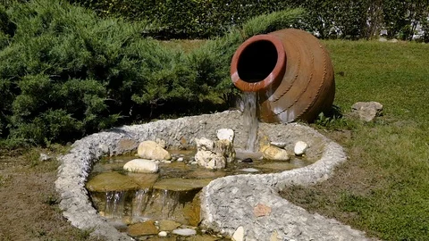 The decor in the Park. Slow motion from a large jug of water flows and becomes a Video stock 92156090