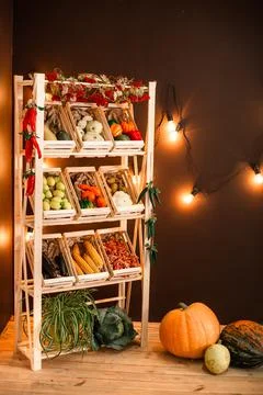 Decor shelf with boxes of vegetables and fruits on a light bulb background Stock Photos