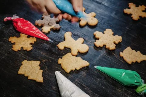 Decorate Christmas gingerbread cookies using colored glaze on a dark wooden t Stock Photos