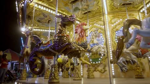 Decorated Carousel Horses Rotating Under Ornate Golden Lights at an Amusement Stock Footage 345891325
