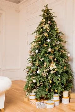 Decorated Christmas tree with golden patchwork ornament, gold balls and big gift Stock Photos