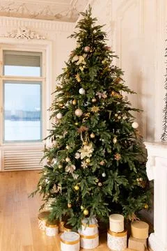Decorated Christmas tree with golden patchwork ornament, gold balls and big gift Stock Photos