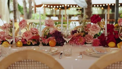 Decorated dining table at an outdoor wedding, with bright flowers and candles Stock Footage 323451311