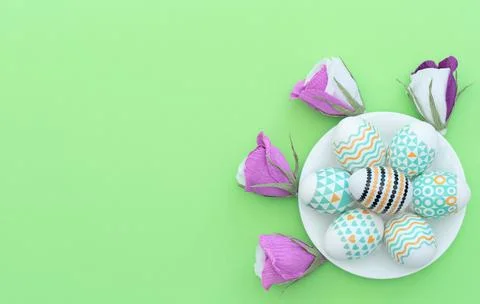 Decorated Easter egg lie on the white plate on green background with flowers  Foto stock