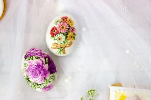 Decorated Easter eggs and flowers on white tulle background; decoupage tech.. Stock Photos