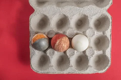 Decorated Easter eggs in a cardboard box on a vibrant red background for se.. Stock Photos