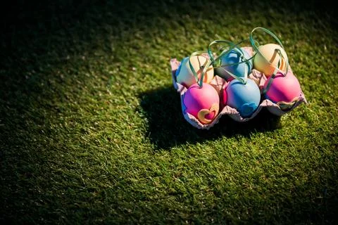 Decorated Easter eggs in crate on grassy field Stock Photos