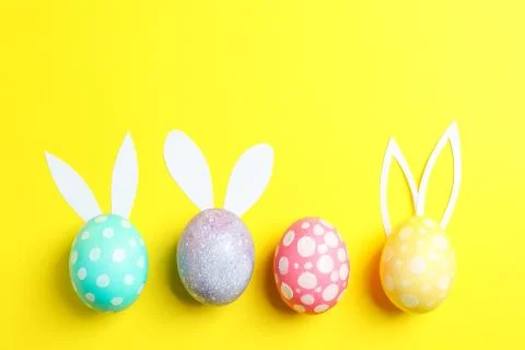 Decorated Easter eggs with cute bunnies ears on yellow background. Space for  스톡 사진