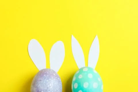 Decorated Easter eggs with cute bunnies ears on yellow background. Space for  Foto stock