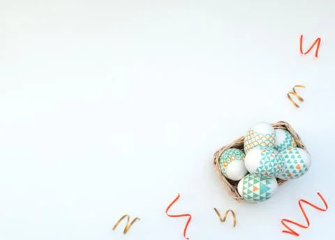 Decorated Easter eggs lie in the basket on white background with bright strea Stock Photos