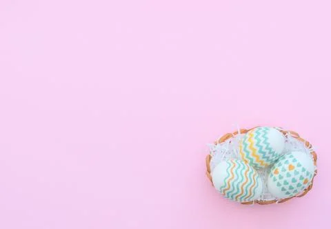 Decorated Easter eggs lie in the basket on pink background. Happy Easter holi Stock Photos