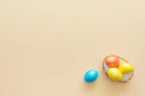 Decorated Easter eggs lie in the basket like a nest on yellow background. Hap Stock Photos