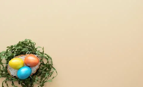Decorated Easter eggs lie in the basket like a nest on yellow background with Stock Photos