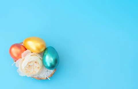 Decorated Easter eggs lie in the basket like a nest with white flower Stock Photos