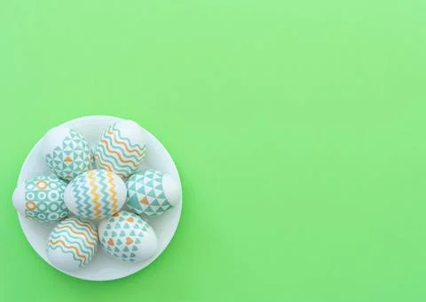 Decorated Easter eggs lie on the white plate on green background. Happy Easte Stock Photos
